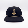 Black anchor baseball cap with gold crest patch and braided trim along brim