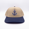 Sand and navy-blue baseball cap with centered anchor patch and curved brim
